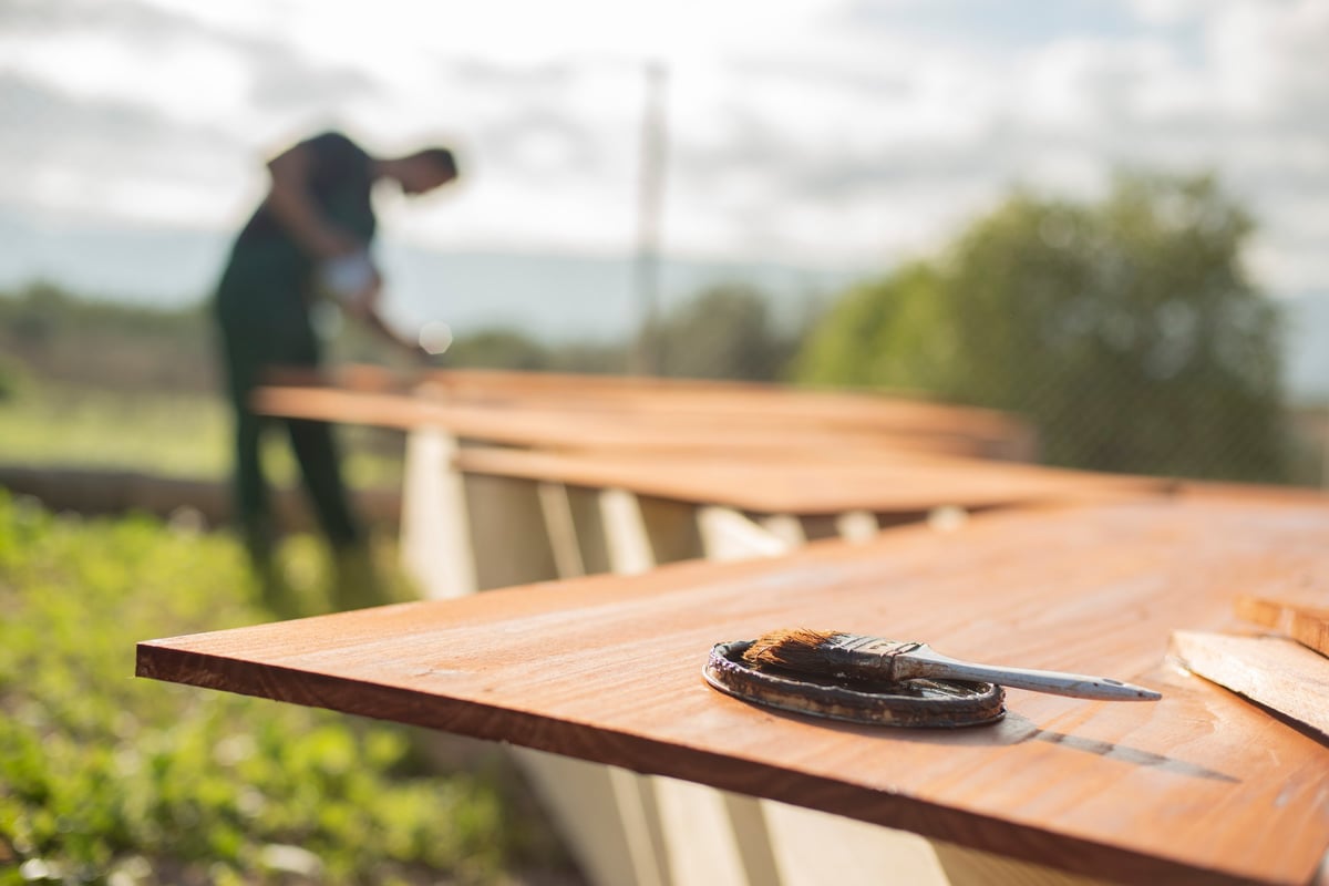 Man applying protective stain to wooden fence