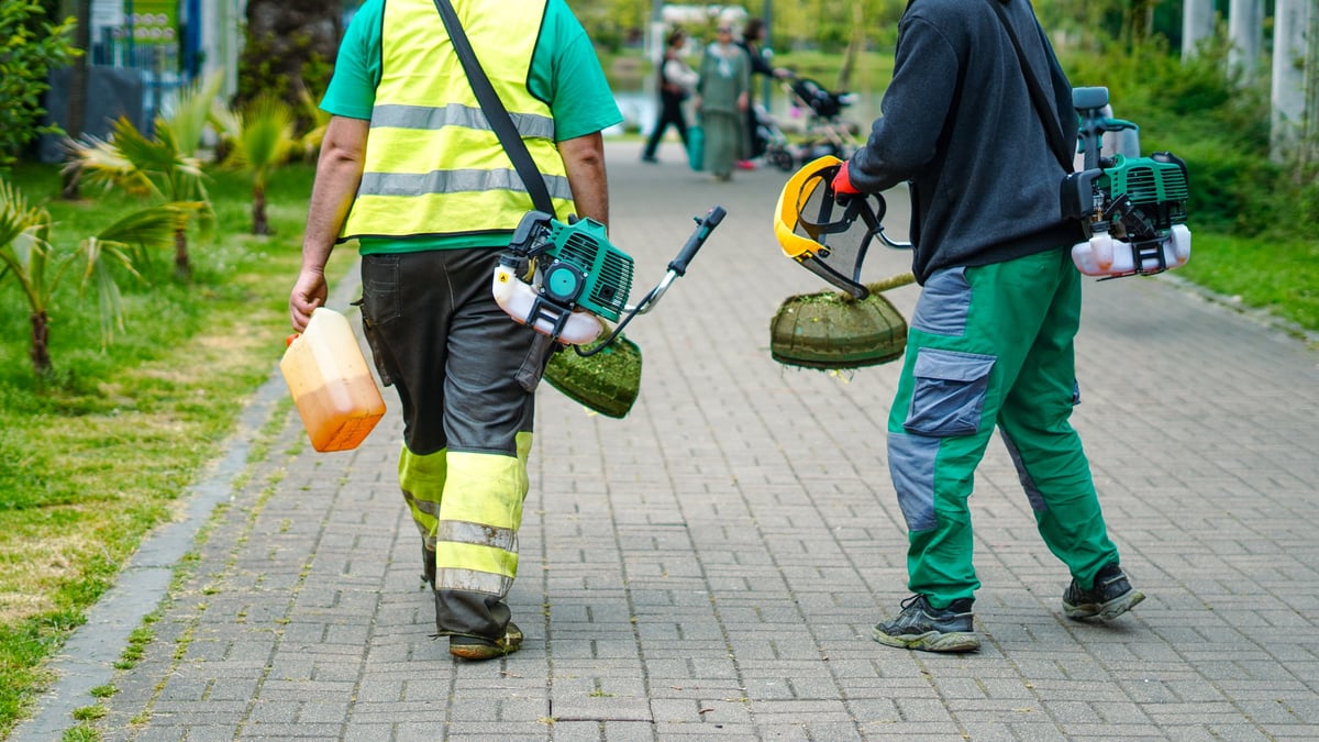 Landscape workers on park path with professional equipment